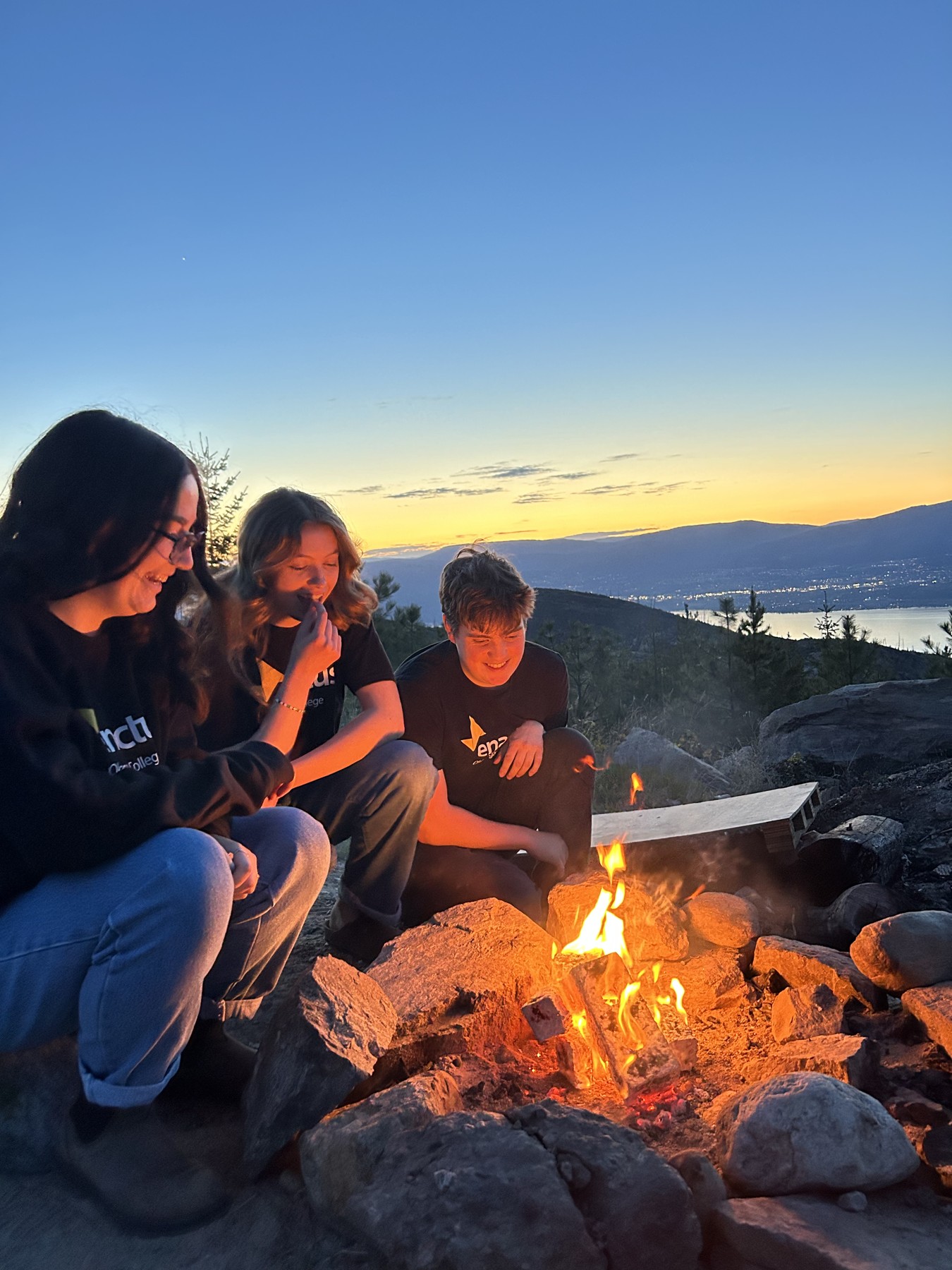 Paper Trail team gathered around a campfire at sunset